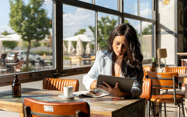 Woman using a digital tablet while sitting in a coffee shop.