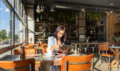 Woman using a digital tablet while working sitting in a coffee shop.