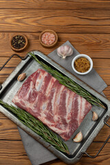 Raw pork ribs on a tray with herbs, spices and garlic