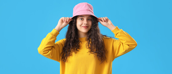 Teenage girl in pink bucket hat on blue background - obrazy, fototapety, plakaty