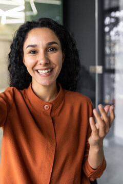 Vertical Shot, Video Call From Office Hispanic Business Woman Working Inside Modern Office Building, Talking Remotely With Friends Using App On Phone For Video Call