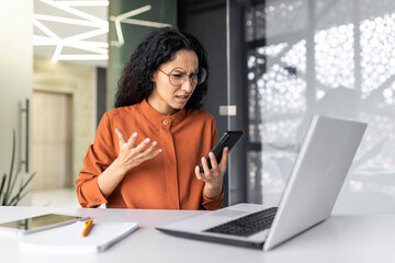 Disappointed and sad woman looking at phone screen, reading bad news online, Hispanic business...