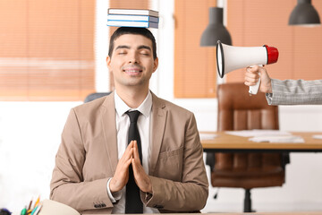 Young businessman with books meditating in office. Balance concept