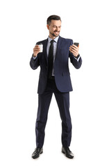 Handsome businessman with cup of coffee and mobile phone on white background