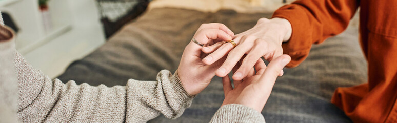 cropped view of gay man wearing wedding ring on hand of boyfriend while making marriage proposal at...