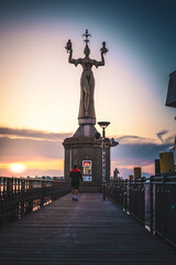 Beautiful sunrise view from wooden pier on Imperia statue at harbor entrance and Lake Constance in...