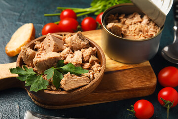 Board with delicious canned tuna, tomatoes and fresh herbs on dark table