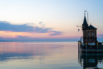 Beautiful sunrise view from Imperia statue to lighthouse at harbor entrance and Lake Constance in...