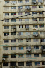 Electric wires and cables stretch between the windows of an apartment complex