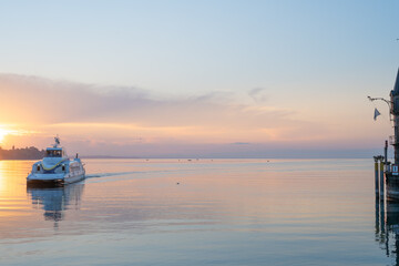 Beautiful sunrise view from Imperia statue at harbor entrance with catamaran ferry on lake...