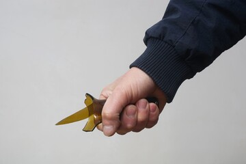 The broken neck of a bottle with a sharp end in a man`s hand.
