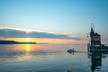 Panoramic sunrise view from Imperia statue to lighthouse at harbor entrance and Lake Constance in...