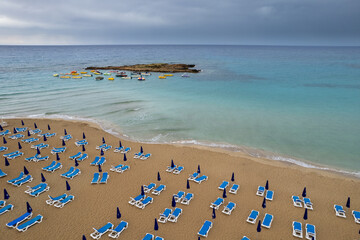Drone aerial of beach chairs in a  tropical sandy beach. Summer holidays in the sea. Protaras Cyprus Europe