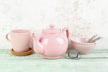 Teapot, mug and bowls with spoons on green wooden table