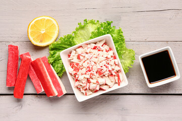 Bowl with tasty chopped crab sticks and sauce on light wooden background © Pixel-Shot