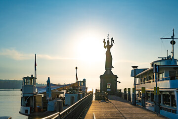 Beautiful sunrise view from wooden pier on Imperia statue at harbor entrance and Lake Constance in...