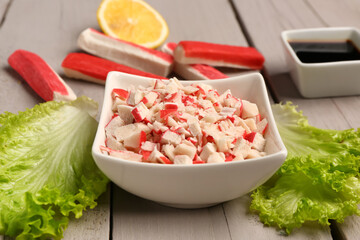 Bowl with tasty chopped crab sticks on light wooden background © Pixel-Shot