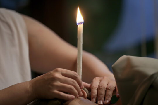 Woman receiving ear candle treatment at spa. Ear coning or thermal-auricular therapy.	
