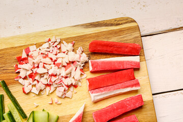 Board with tasty crab sticks on light wooden background © Pixel-Shot