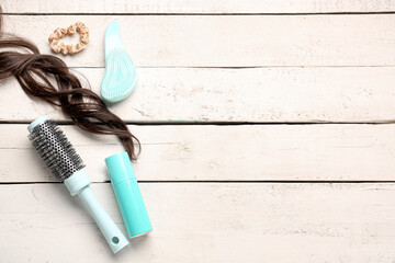 Curly brown hair with brushes, spray and scrunchy on white wooden background