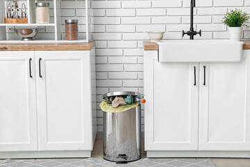 Full trash bin in interior of modern kitchen