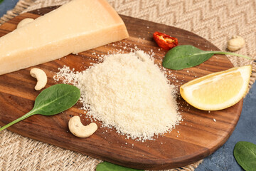 Wooden board with tasty grated Parmesan cheese on table, closeup