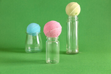 Bottles with bath bombs on green background