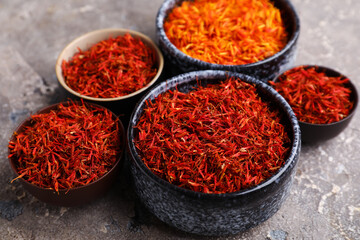 Bowls with pile of saffron on grey grunge background