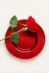 Plate with beautiful red rose on light background