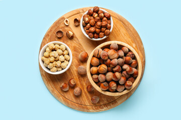 Board and bowls with hazelnuts on blue background