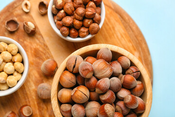Board and bowls with hazelnuts on blue background