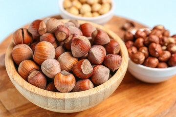Board and bowls with hazelnuts on blue background
