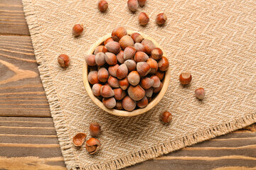 Bowl with shelled hazelnuts on wooden background
