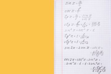 Copybook with maths formulas on yellow background