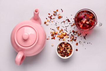 Ceramic teapot with cup of tea and dried fruits on grey background © Pixel-Shot