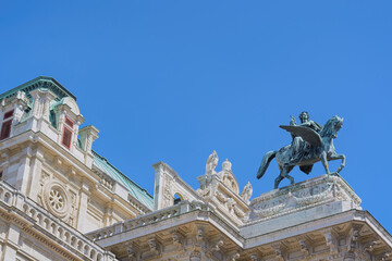 View of the blue sky and the upper part of the Vienna Opera building with sculpture