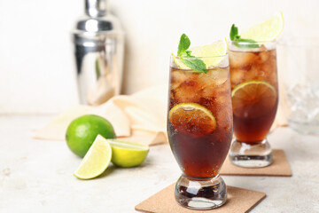 Glasses of cold Cuba Libre cocktail on light background