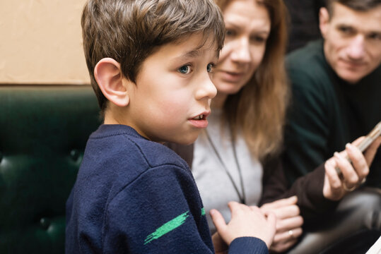 A young boy stands in front of his parents who are trying to tell him something, educate him, boy is distracted and does not listen to his parents, the concept of upbringing