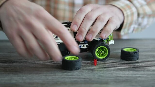  A father assembles a machine constructor from parts for his son. A man repairs a childrens car.