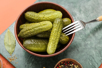 Board with bowl of tasty canned cucumbers and ingredients on red background