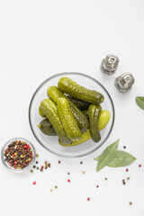 Bowl of tasty canned cucumbers with spices on white background