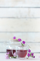 Pretty tea set with delicate flowers on white table near wooden wall