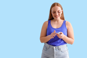 Woman with diabetes using digital glucometer on light blue background