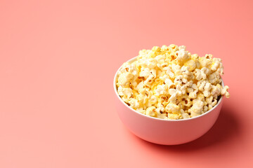 Bowl with crispy popcorn on pink background