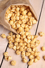 Paper bag with crispy popcorn on white wooden background
