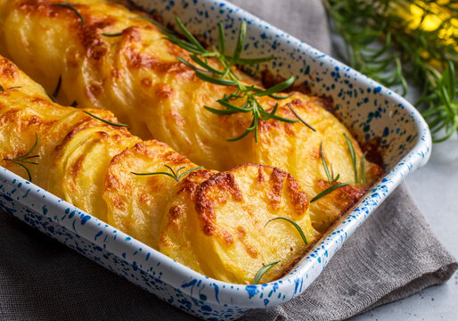 Potato gratin - graten (baked potatoes with cream and cheese) with rosemary and forks (Turkish name; Kremali patates)