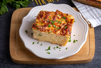 Pasta casserole bechamel sauce topped with melted mozzarella cheese and served in a white baking dish on a table (Turkish name; firinda makarna or firin makarna)