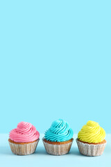 Tasty colorful cupcakes on blue background
