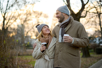 Fototapeta premium A happy romantic couple with coffee walking in the park