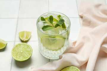 Glass of tasty mojito on white tile background